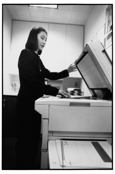 a woman making copies on a copy machine.